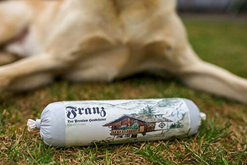 Saucisse pour chien sur l'herbe avec un chien en arrière-plan.